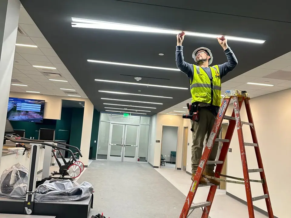 J&K Electric technician installing linear LED lighting in a commercial corridor